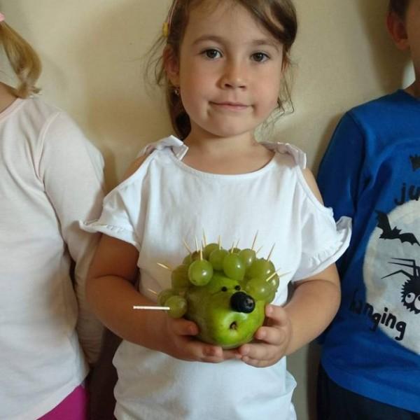 jez-z-gruszki-i-winogron-trzymany-przez-dziecko